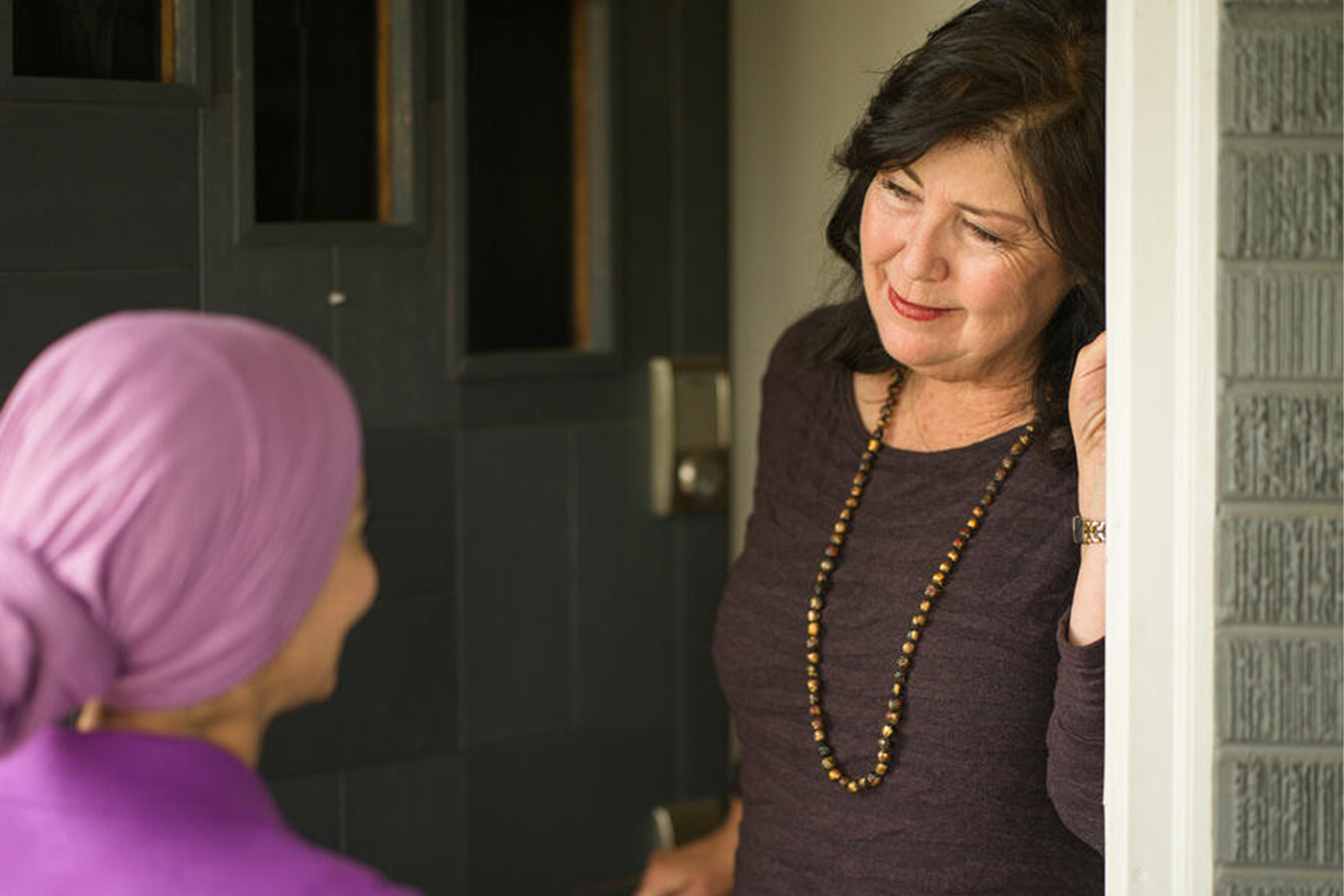 A host welcomes a guest at the doorway of a home in an Airbnb.org program photograph.
