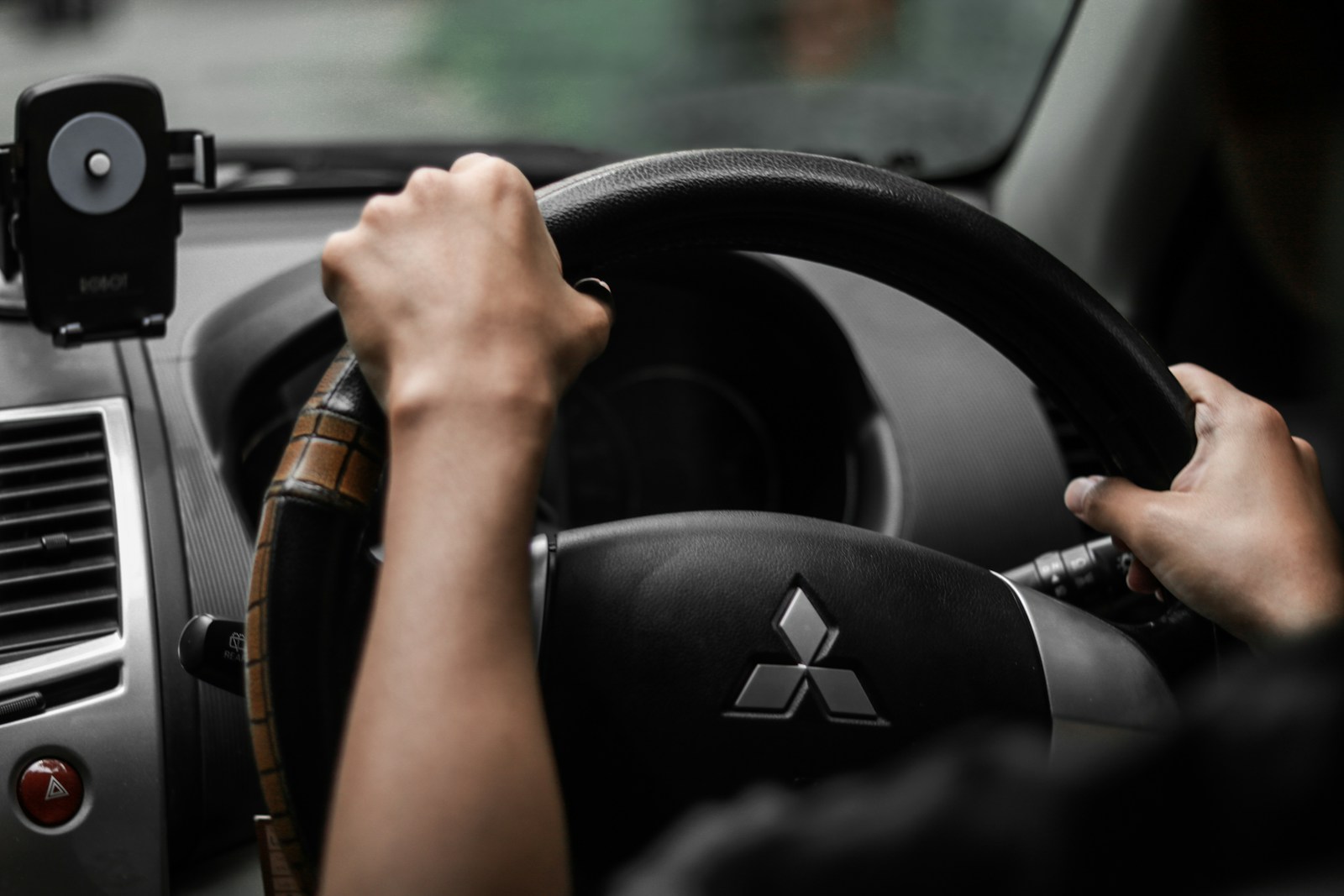 A driver's hands on a steering wheel inside a vehicle.